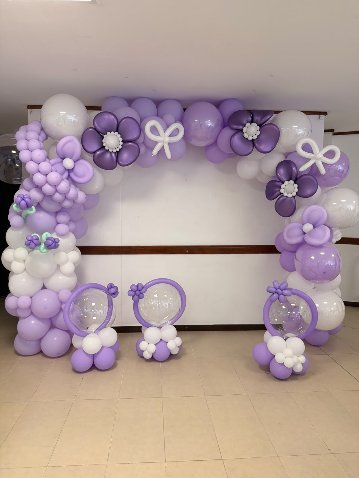 Arco de globos lila y blanco con flores de globo y burbujas transparentes