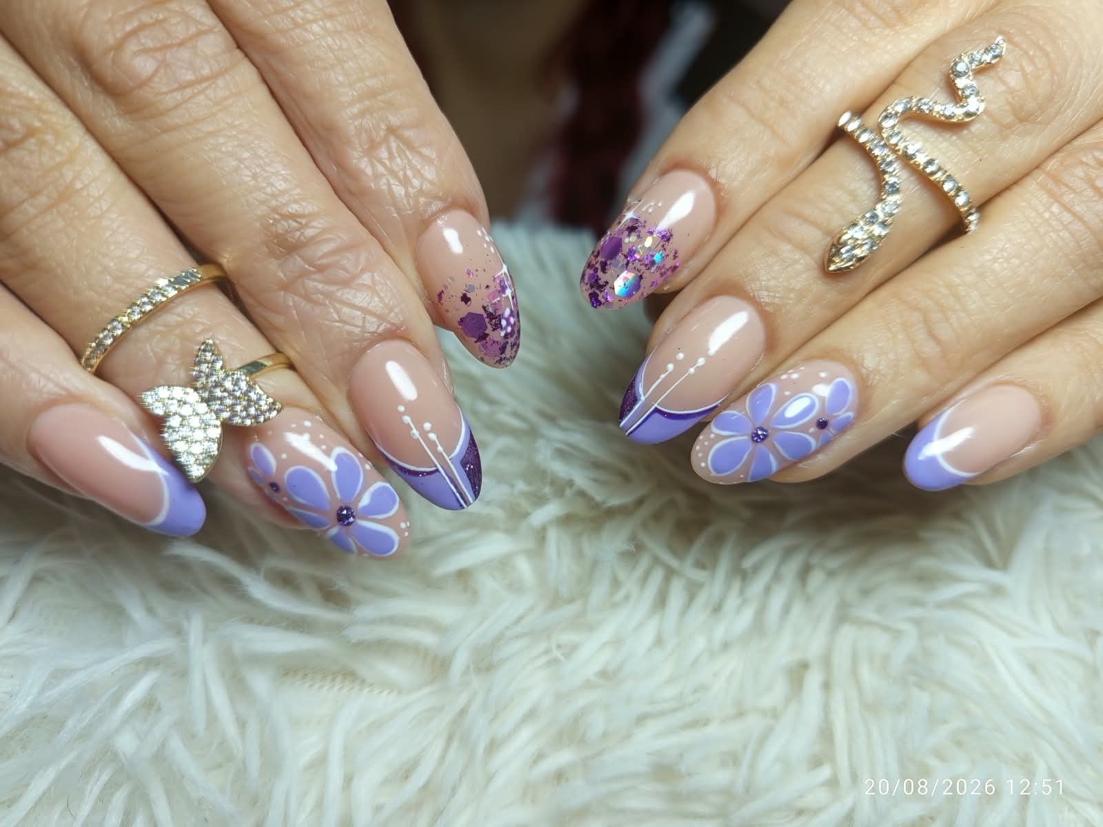 Uñas lila con flores pintadas a mano y glitter