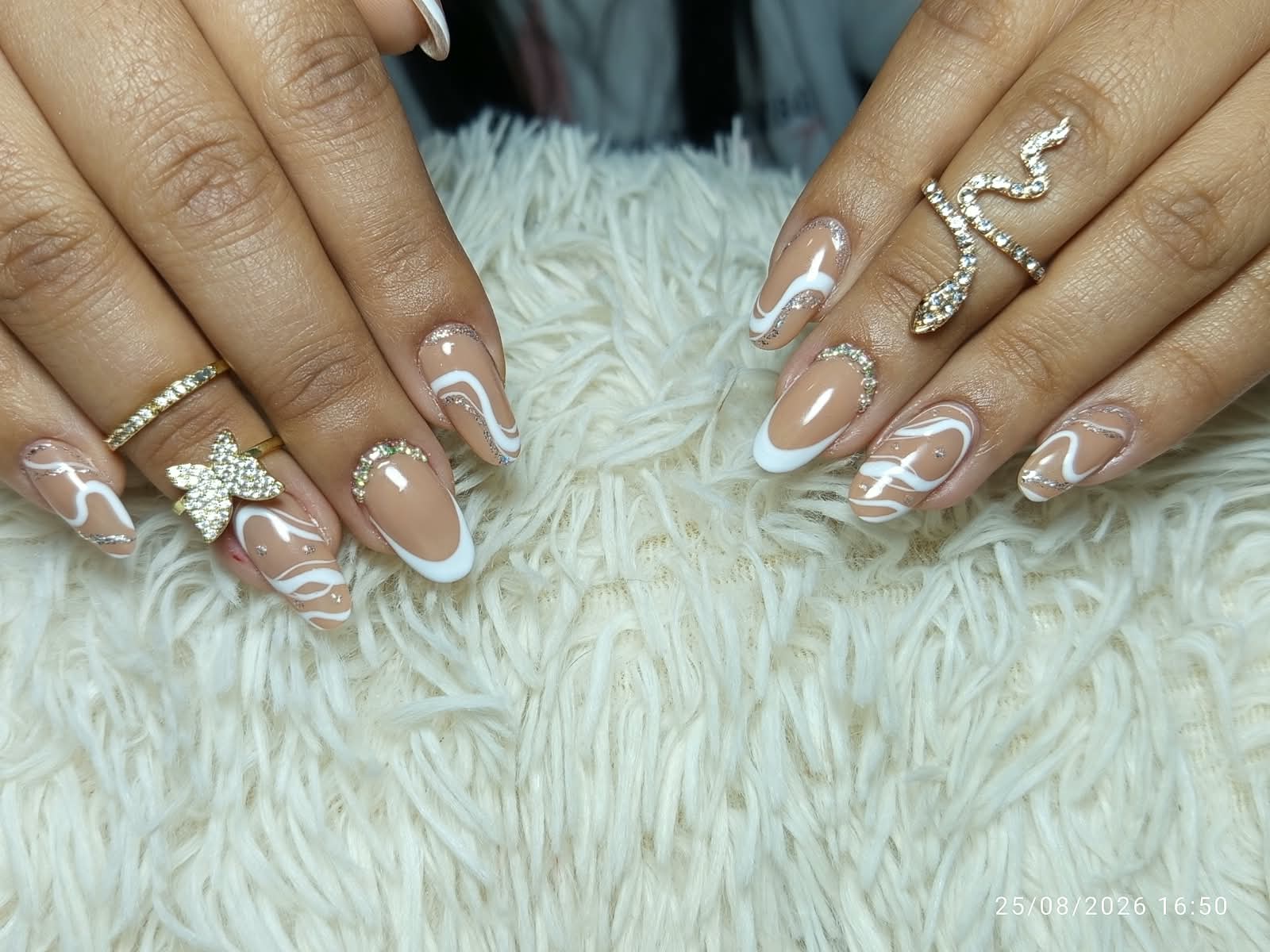 Uñas nude con ondas blancas y glitter dorado